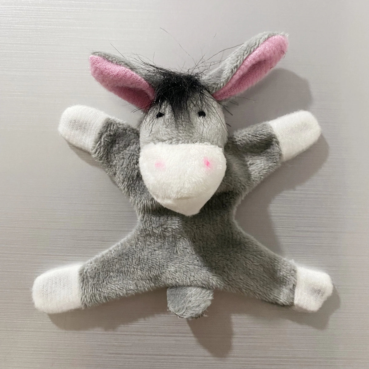 A gray elephant fridge magnet with pink ears and white accents.