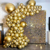 A large balloon garland made of metallic gold balloons decorated against a textured gold background.