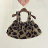 A leopard print shoulder strap skirt for dolls made of brown fabric is displayed on a wooden hanger.