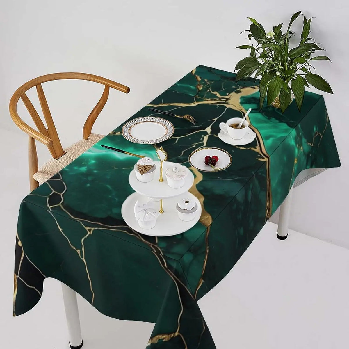 Mantel verde oscuro con textura de mármol dorado, puesto para una comida festiva, con platos y cubiertos blancos.