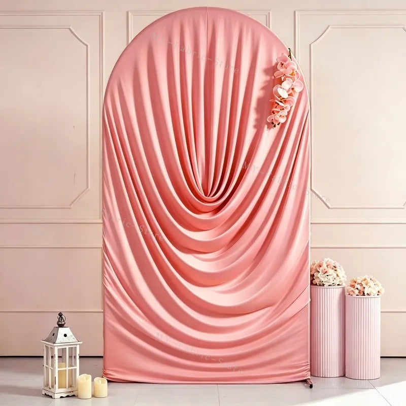 A pink stretchy spandex arch cover draped elegantly with peach floral accents for weddings and events.