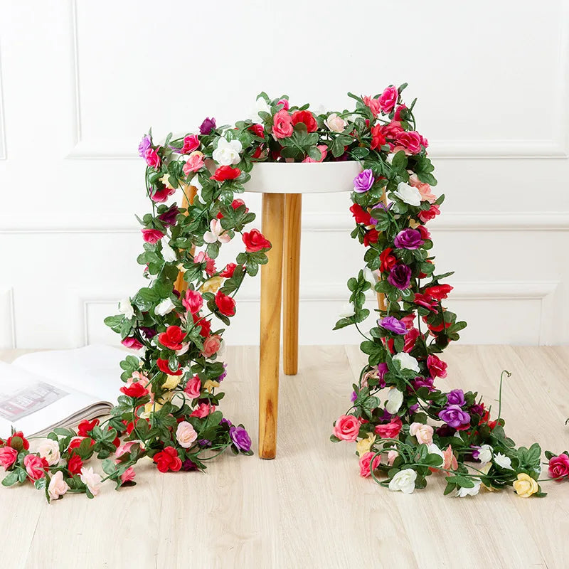 A lush silk rose garland featuring pink, red, and purple flowers draped on a white wooden stand.