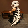 A white dinosaur skeleton plush costume resembling a large rib cage is displayed on a wooden table.