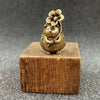 A brass figurine of a hedgehog with a leaf and flower detail, resting on a wooden block.