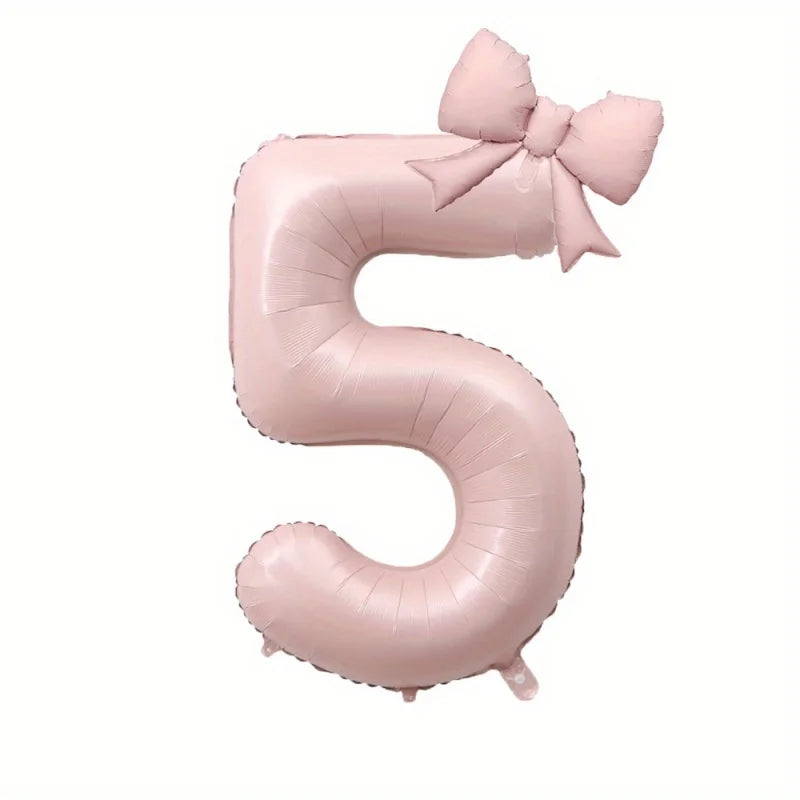 A large pink foil number balloon shaped like the number 5 with a bow.