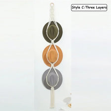 Three layers of macrame hat organizers with wooden dowels in shades of olive green, terracotta, and gray.
