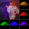 A woman posing with a sparkly silver dress, surrounded by various glowing LED folding fans in different colors.