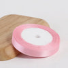 Pink silk satin ribbon rolled on a wooden cutting board.