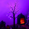 Dunkle Baumsilhouette mit leuchtend lila LED-Lichter vor dunklem Hintergrund.