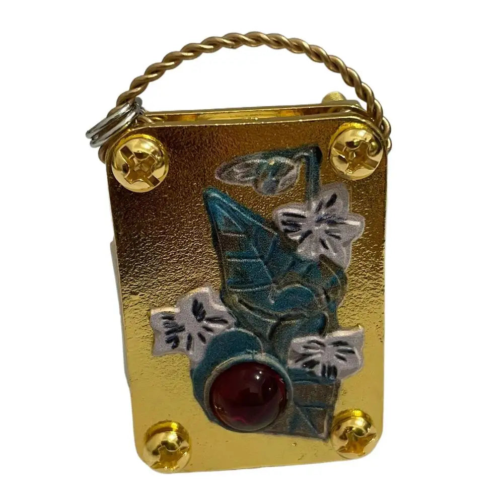A small gold-toned metal press kit with a wire loop, featuring a pressed blue leaf and a red bead.