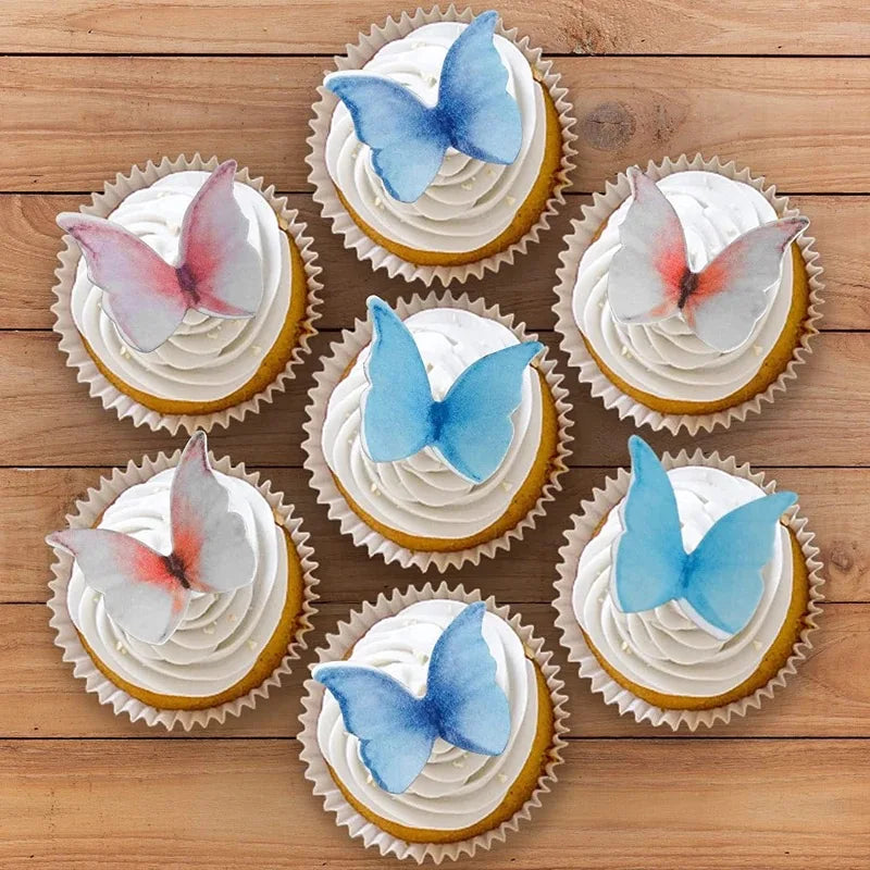 A collection of cupcakes decorated with butterfly toppers in shades of pink, blue, and white on a wooden surface.