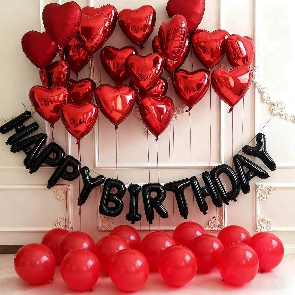 A black heart balloon banner and a collection of red balloons for a birthday celebration.