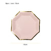 A pink, gold-edged disposable plate with a hexagonal shape, used for party tableware.