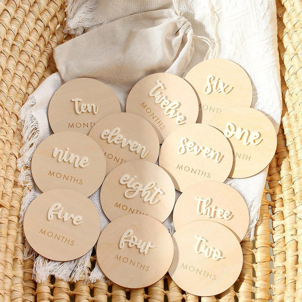 A collection of round wooden milestone cards numbered one through ten, arranged on a woven mat.
