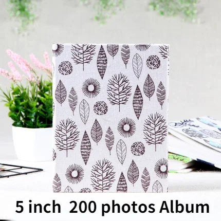 A white fabric memory album featuring a repeating pattern of black leaf silhouettes.