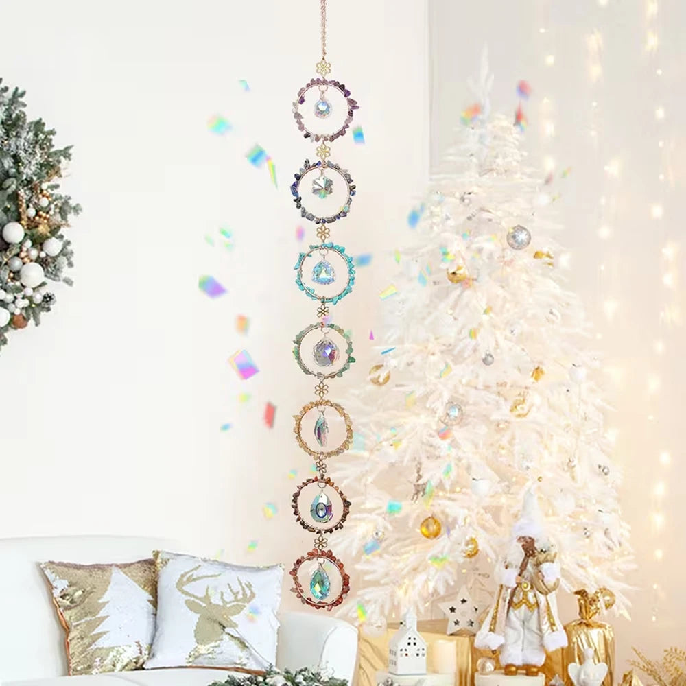 A crystal sunshine catcher set hangs on a white wall next to a decorated white Christmas tree.