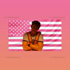 A man wearing a t-shirt is positioned in front of an American flag background with pink and white stripes and stars.