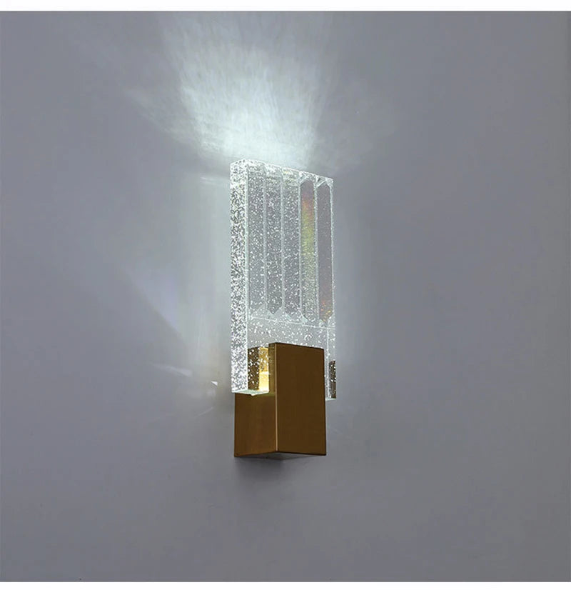 Modern bubble crystal LED wall sconces mounted on a gray wall, emitting a bright light.
