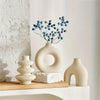 A ceramic vase set featuring a large, smooth, off-white vase with blue berries and a smaller, curved vase on a wooden surface
