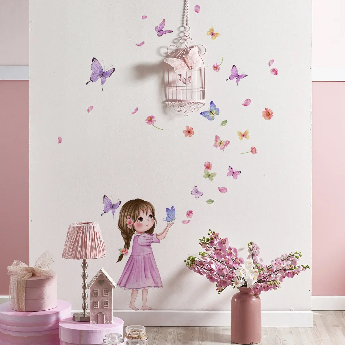 A figurine of a girl in a pink dress stands next to a wall decorated with butterfly stickers and pink floral arrangements.