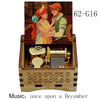A hand-cranked wooden music box featuring an illustration of two characters, with the title Once Upon a December visible.
