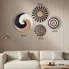 A collection of round boho straw wall hangings with geometric patterns in black, white, and natural tones displayed on a beig