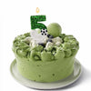 A green frosted cake shaped like the number 5 decorated with soccer-themed elements and a lit candle.
