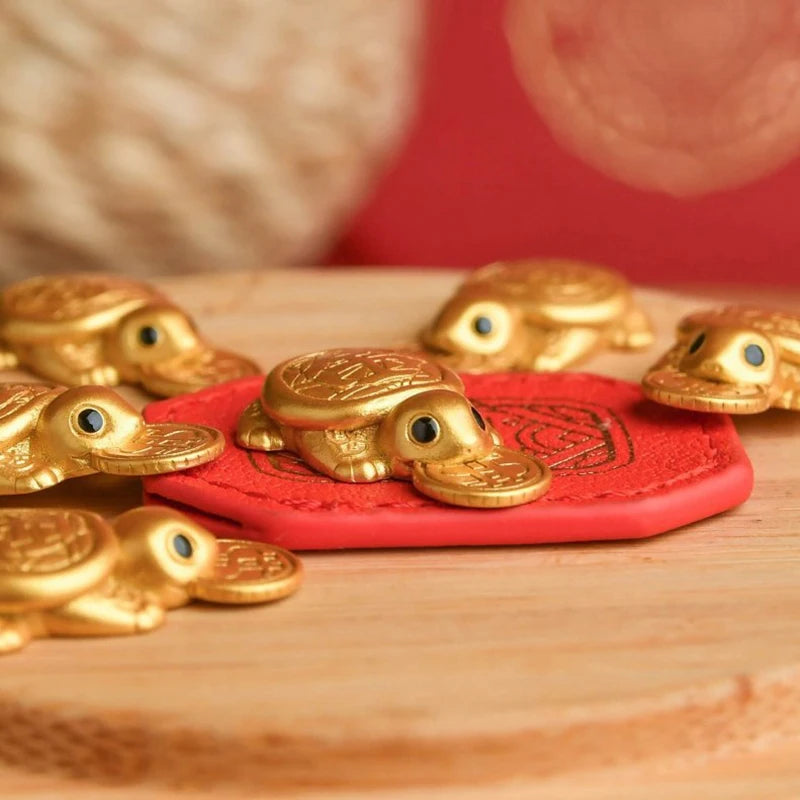 A collection of golden tortoise figurines resting on a red felt pad on a wooden surface.