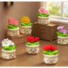 A collection of small potted rose resin charms in various colors like pink, yellow, and purple displayed on a wooden surface.