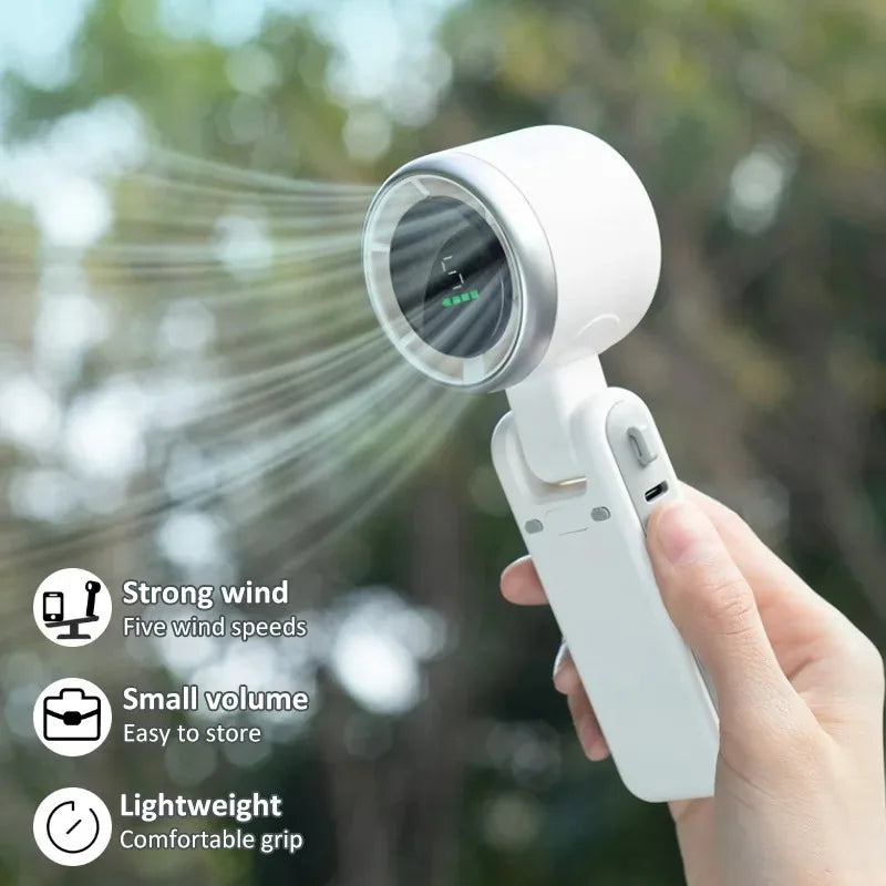 A hand holds a white foldable mini handheld fan emitting a strong wind, demonstrating its features.