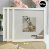 A set of three white photo frames displayed on a light-colored surface with floral decorations.