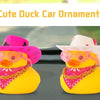 Two yellow rubber duck car ornaments with pink cowboy hats displayed on a car dashboard.