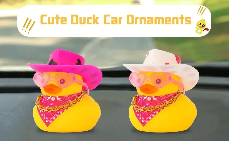 Two yellow rubber duck car ornaments with pink cowboy hats displayed on a car dashboard.