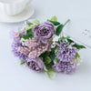 A bouquet of artificial silk peony flowers in shades of lavender and purple on a white surface.