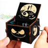 A carved wooden music box with a lid featuring a skull and bat design against a moon background.