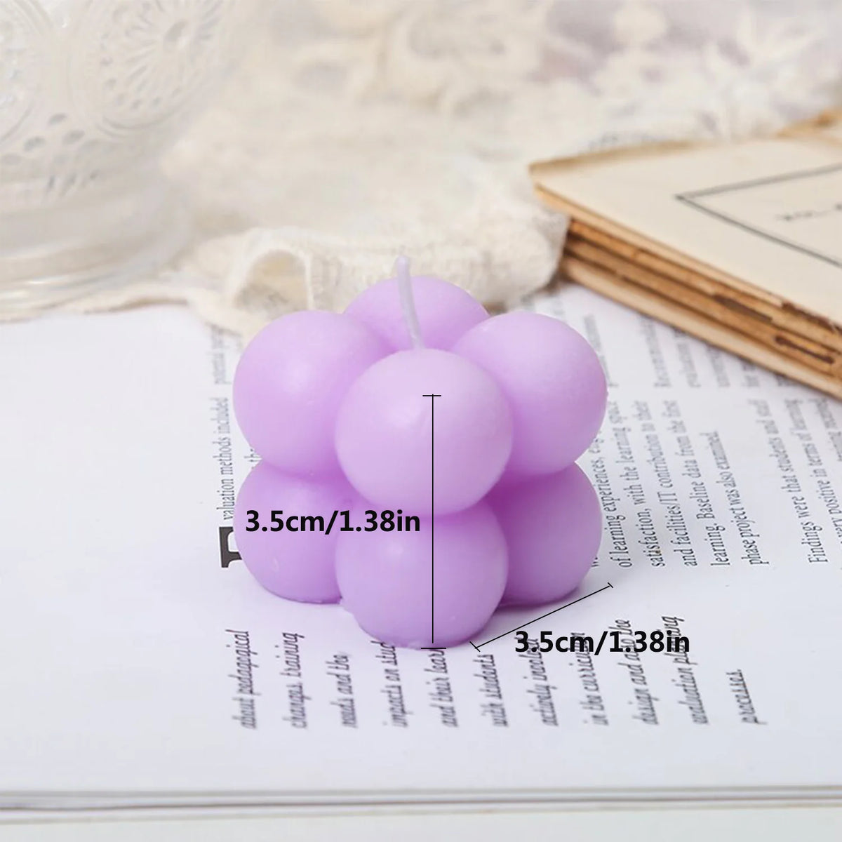 A set of two pink soy wax candles resting on a white notebook with measurement lines.