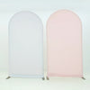 A pair of stretchable arch backdrop covers, one white and one blush pink, displayed against a light background.