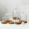Clear glass aromatherapy candle holders with wooden bases and decorative lids arranged on a white surface.
