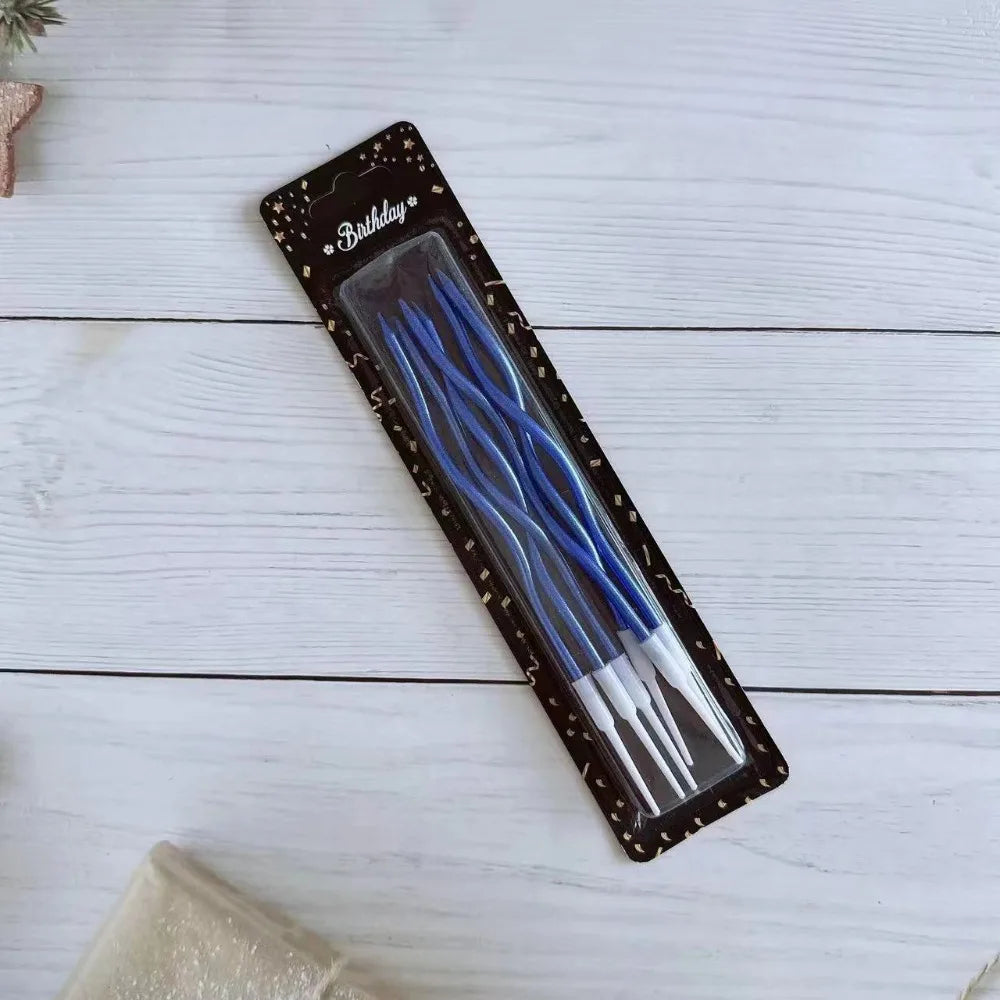 A package of long thin blue birthday candles with white tips displayed on a white wooden surface.