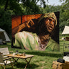 A large banner featuring a portrait of a person with dreadlocks and green clothing, displayed outdoors in a grassy field.