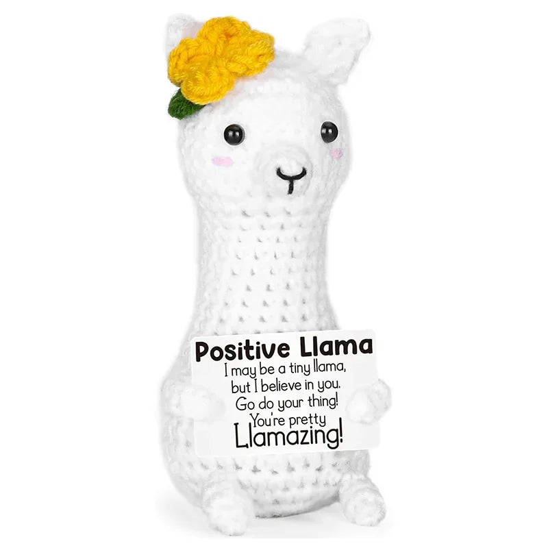 A white crocheted llama doll with yellow flowers and a card that reads Positive Llama
