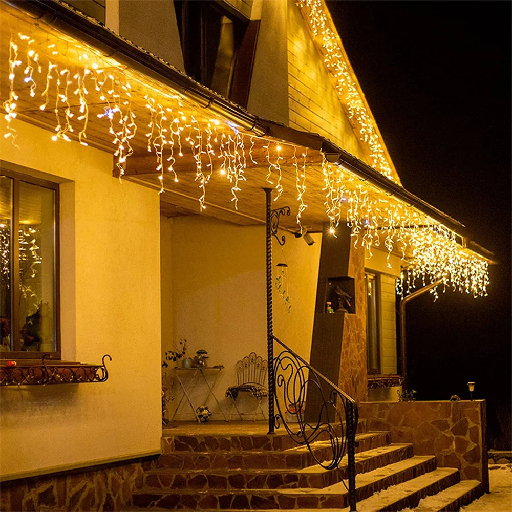 Warm yellow string lights drape over a house facade and steps at night.