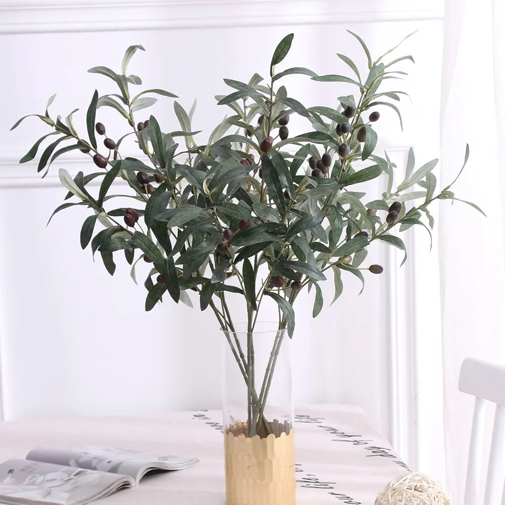 Artificial olive branch with dark green leaves and small fruits displayed in a glass vase.