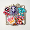 Silver glitter acrylic charms featuring a purple alien, a blue shirt, and a puppy face.
