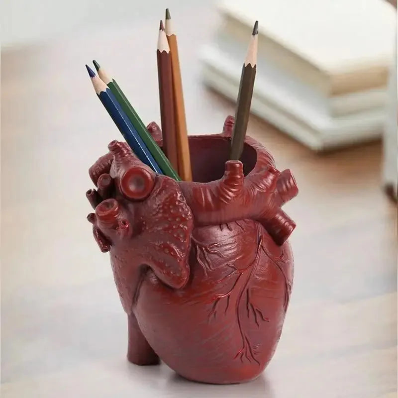 A terracotta heart-shaped resin organizer filled with colored pencils and a charcoal pencil.