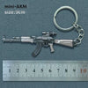 A silver miniature AKM assault rifle model attached to a metal keyring, shown next to a ruler.