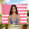 A woman wearing a blue sparkly top stands in front of a pink and white striped flag tapestry.