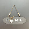 Rustic wooden door welcome sign with the word HOME cut into the wood and suspended by twine