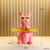 A pink decorative bulldog figurine wearing sunglasses and a bow tie, displayed on a golden tray.