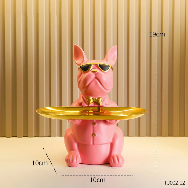 A pink decorative bulldog figurine wearing sunglasses and a bow tie, displayed on a golden tray.
